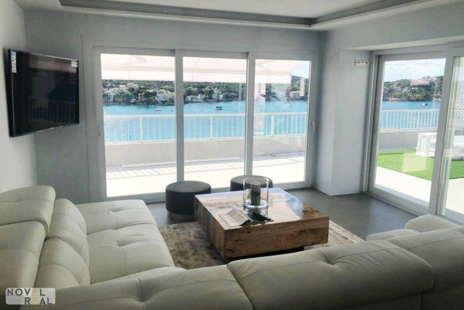 Helles Wohnzimmer mit bequemen Sofas, Holztisch und großen Schiebetüren zum Meerblick.