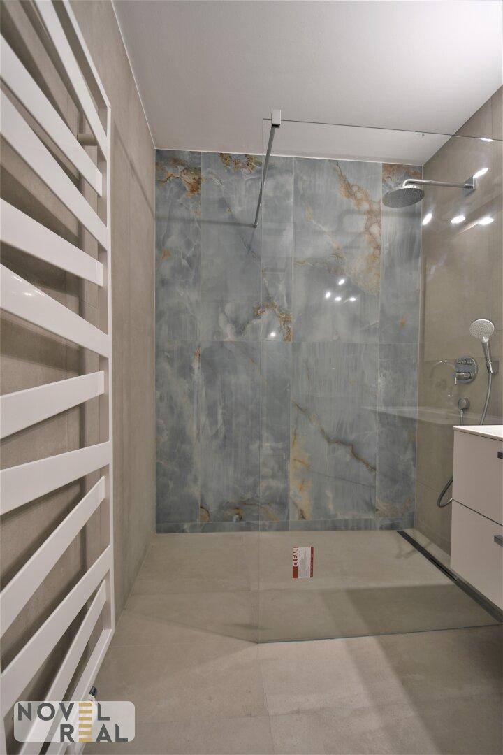 Modernes Badezimmer mit großer begehbarer Dusche, Regendusche und Handtuchheizkörper.