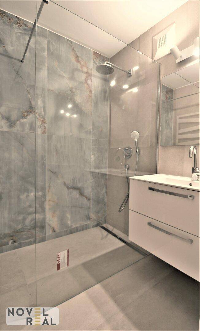 Elegantes Badezimmer mit begehbarer Dusche, modernem Waschtisch und Spiegel.