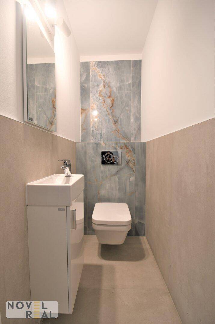 Separates WC mit wandhängender Toilette und kleinem Waschtisch in modernem Design.