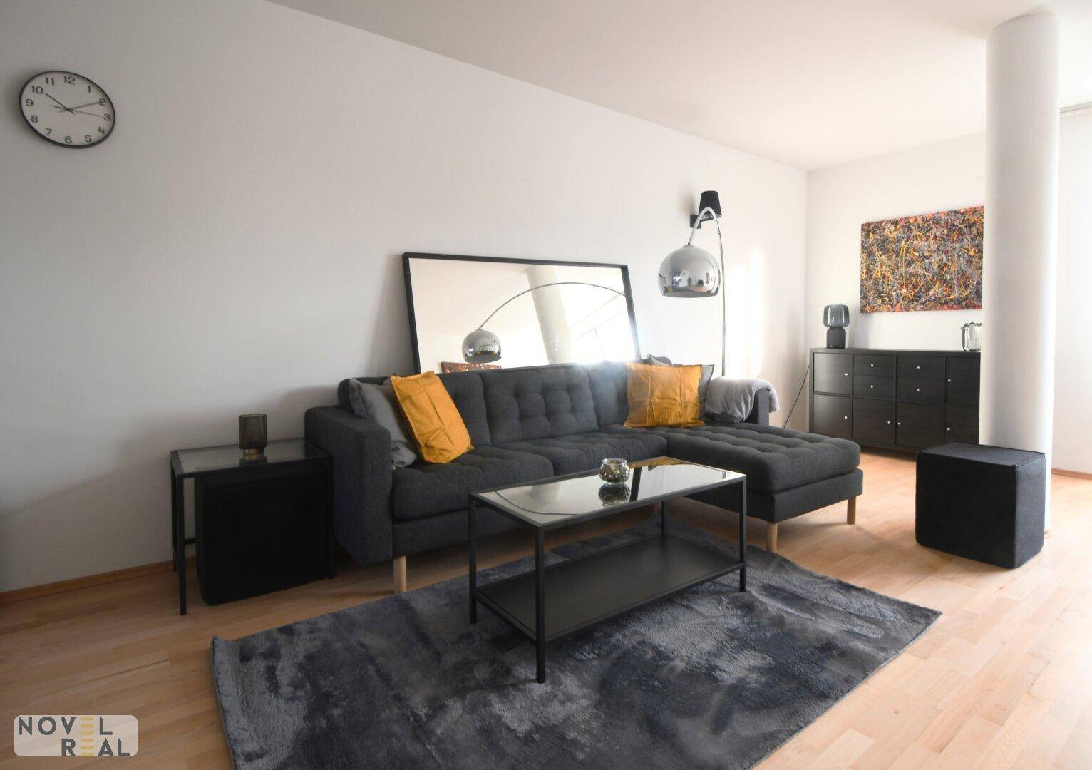 Gemütliches Wohnzimmer mit großem Ecksofa, Couchtisch und modernem Teppich.