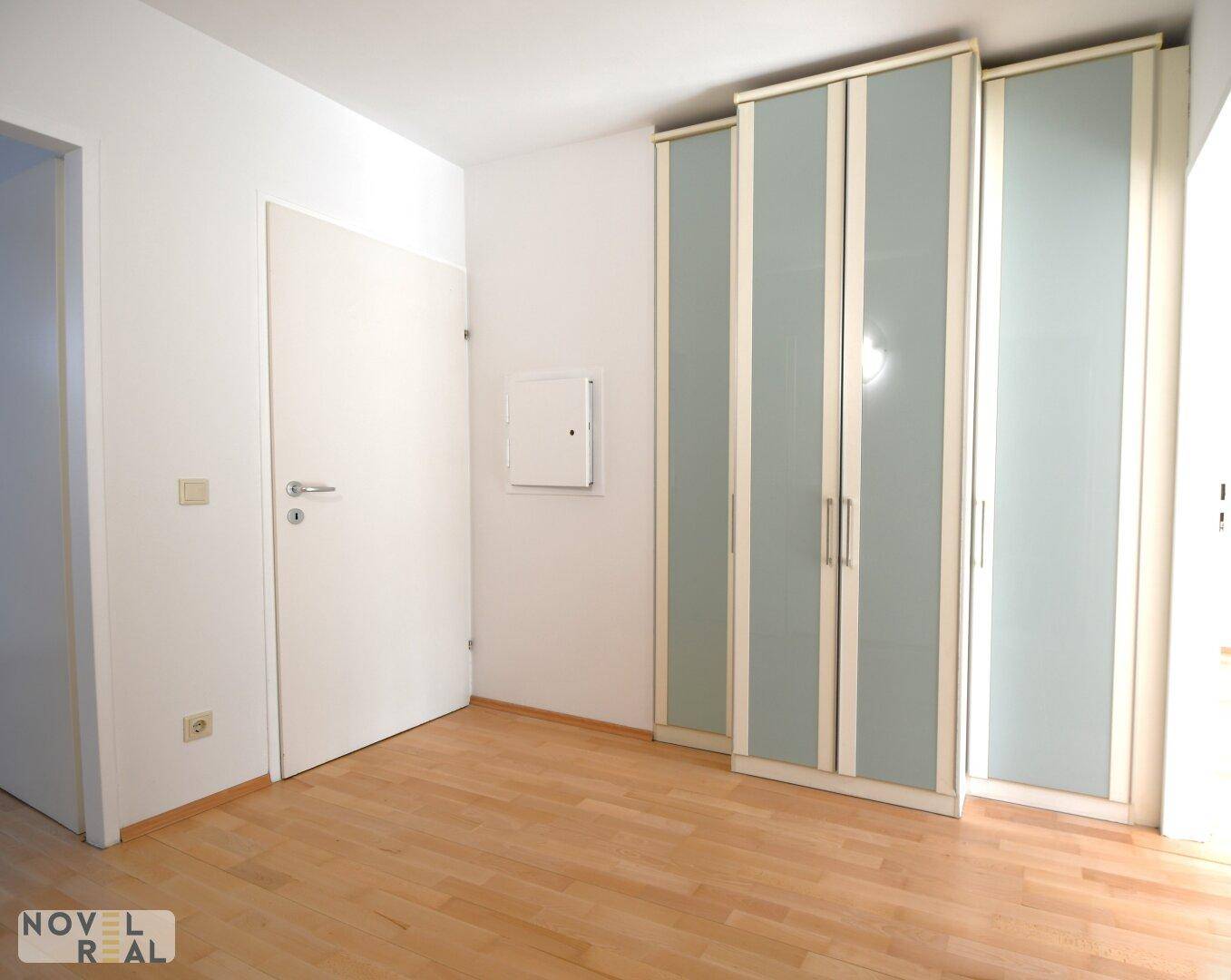 Leeres Zimmer mit hellem Parkettboden und einem Kleiderschrank, ideal als Schlafzimmer.