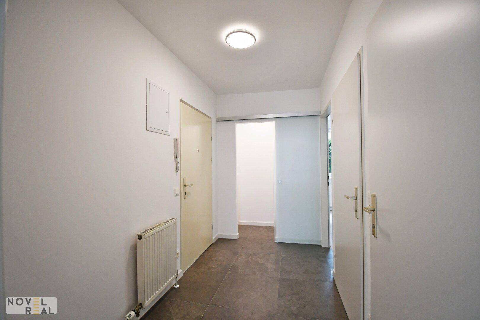 Heller Flur mit Fliesenboden und Zugang zu verschiedenen Räumen.