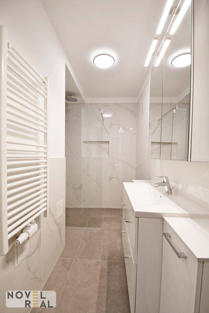 Modernes Badezimmer mit großformatigen Fliesen, Waschtisch und begehbarer Dusche.