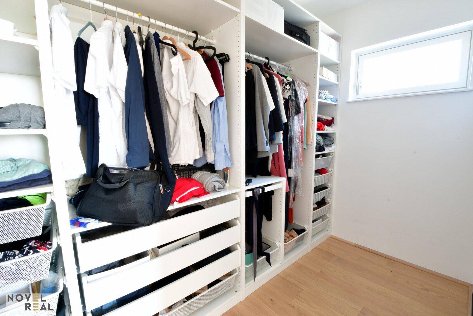 Begehbarer Kleiderschrank mit umfangreichen Regalsystemen und einem kleinen Fenster.