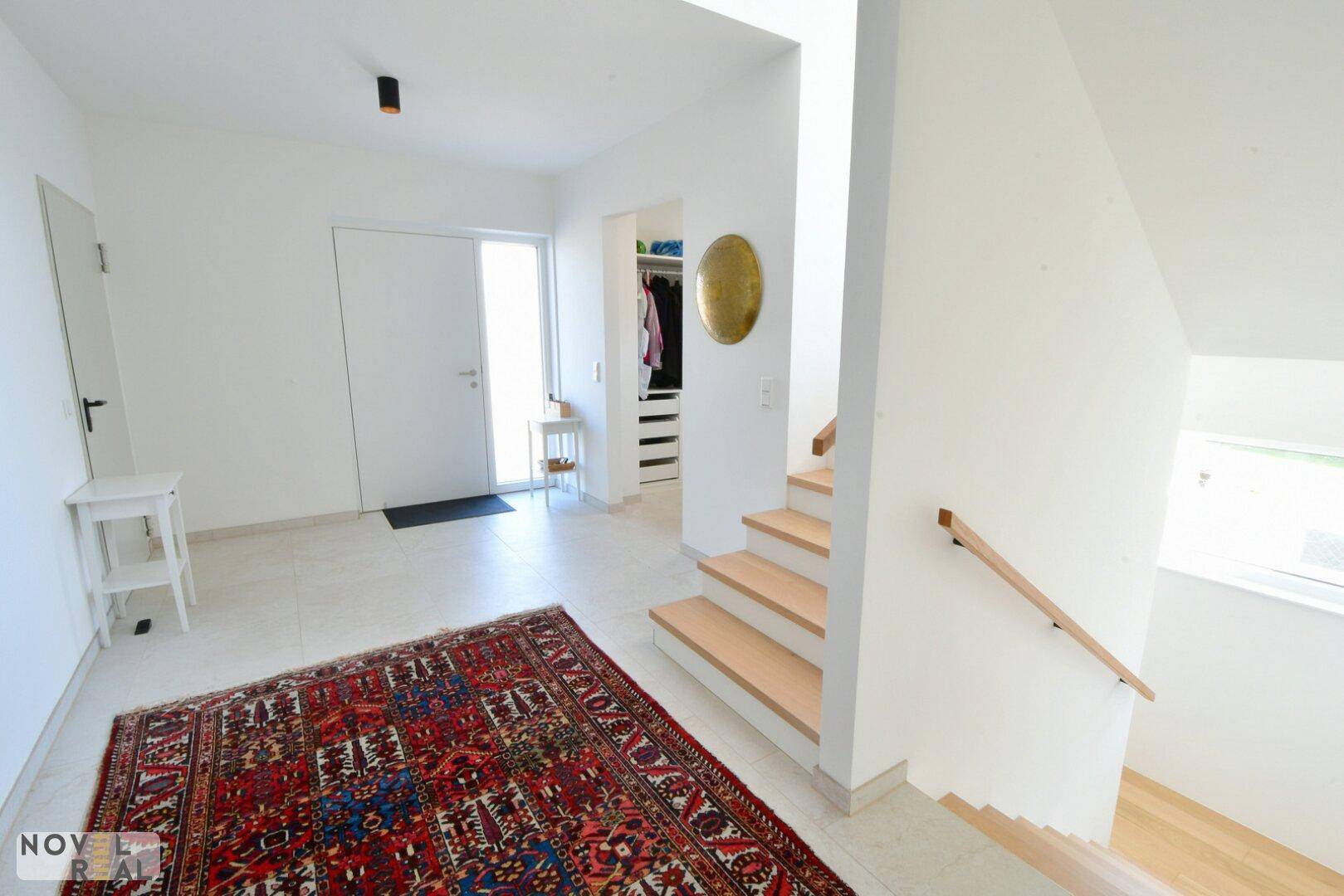 Geräumiger Eingangsbereich mit Fliesenboden, Treppe und Zugang zu einem begehbaren Kleiderschrank.