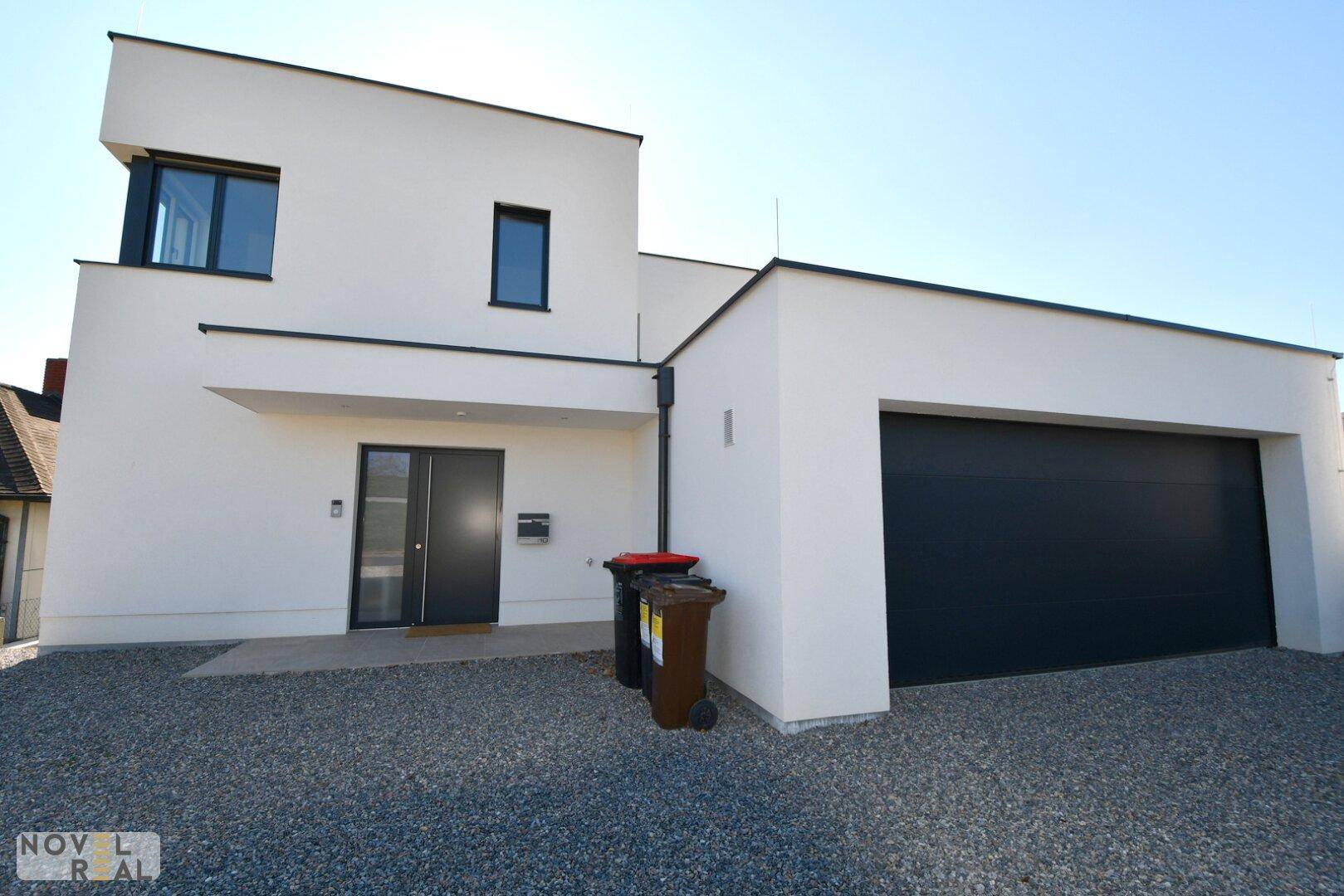 Moderne Hausfassade mit integrierter Garage und Kiesauffahrt.