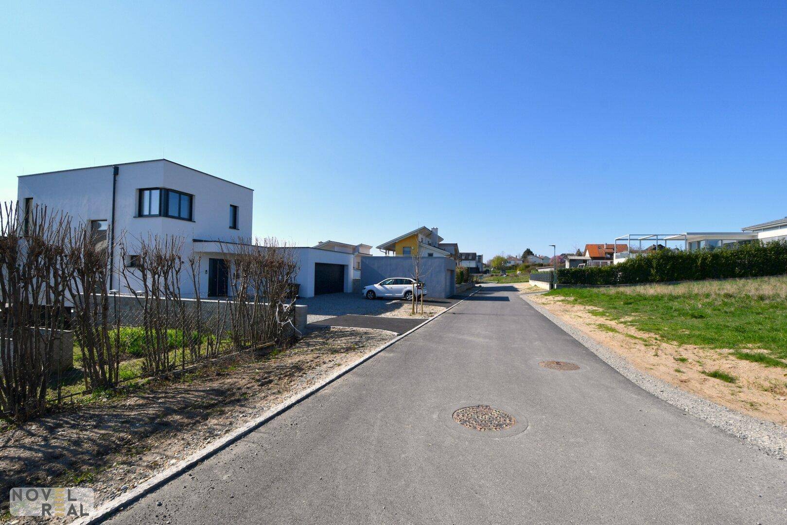 Ruhige Wohnstraße mit modernen Häusern und Grünflächen in der Umgebung.