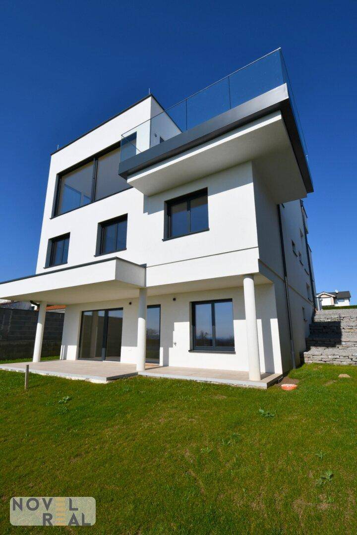 Moderne weiße Villa mit großen Fenstern und Zugang zum Gartenbereich.