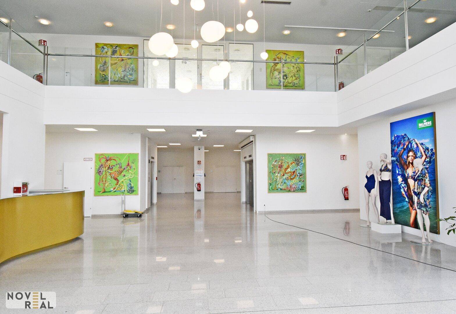 Geräumige, moderne Lobby mit hoher Decke, Kunstwerken und Schaufensterpuppen, sehr einladend.