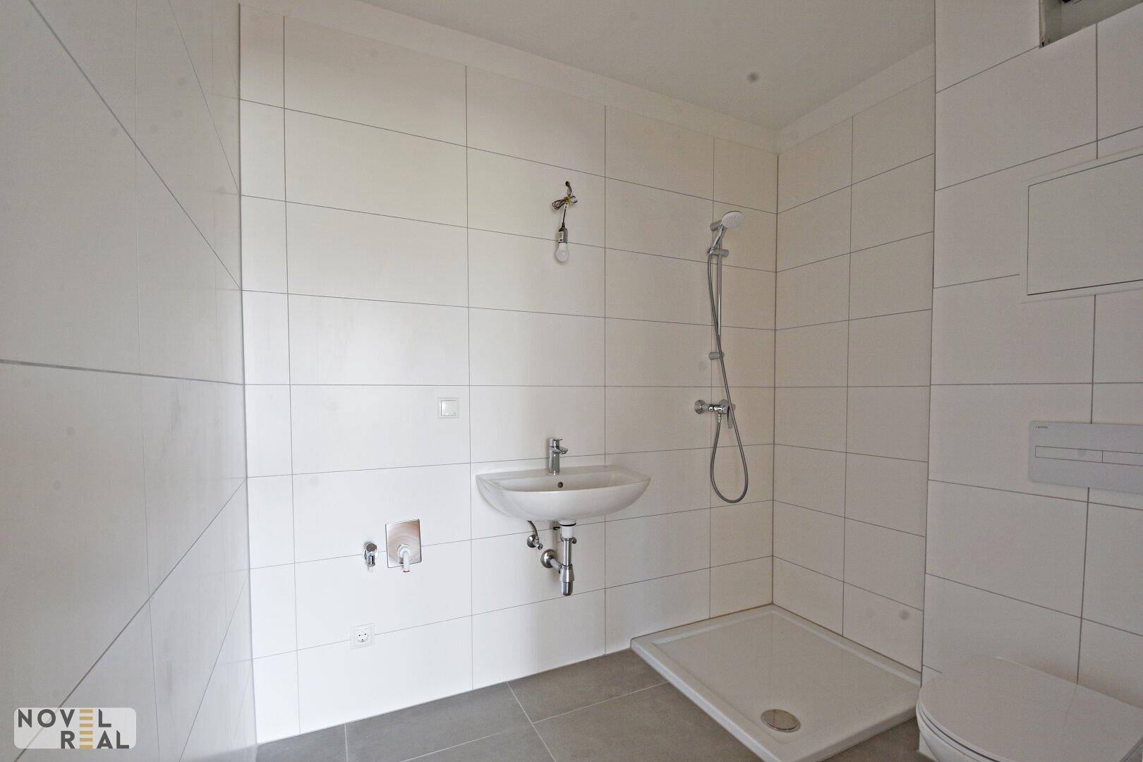 Modernes Badezimmer mit weißen Fliesen, Dusche und Waschbecken, noch im Bau.