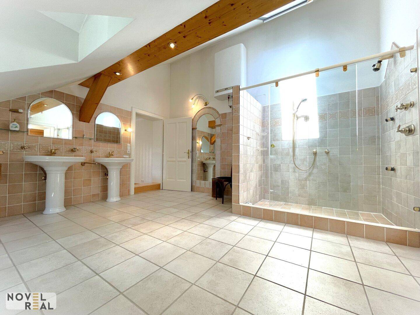 Geräumiges Badezimmer mit zwei Waschbecken, großer Dusche und Fliesenboden.