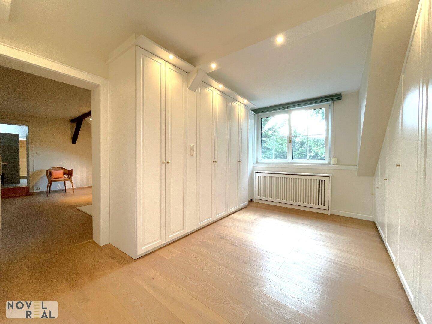 Schlafzimmer mit Einbauschränken, Holzboden und großem Fenster.