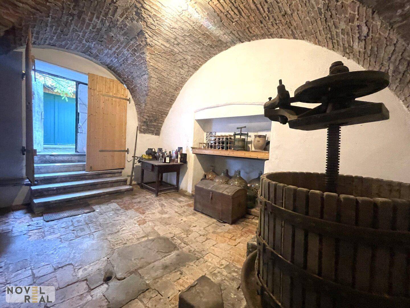 Historischer Weinkeller mit Ziegelgewölbe, Steinboden und Weinpresse.