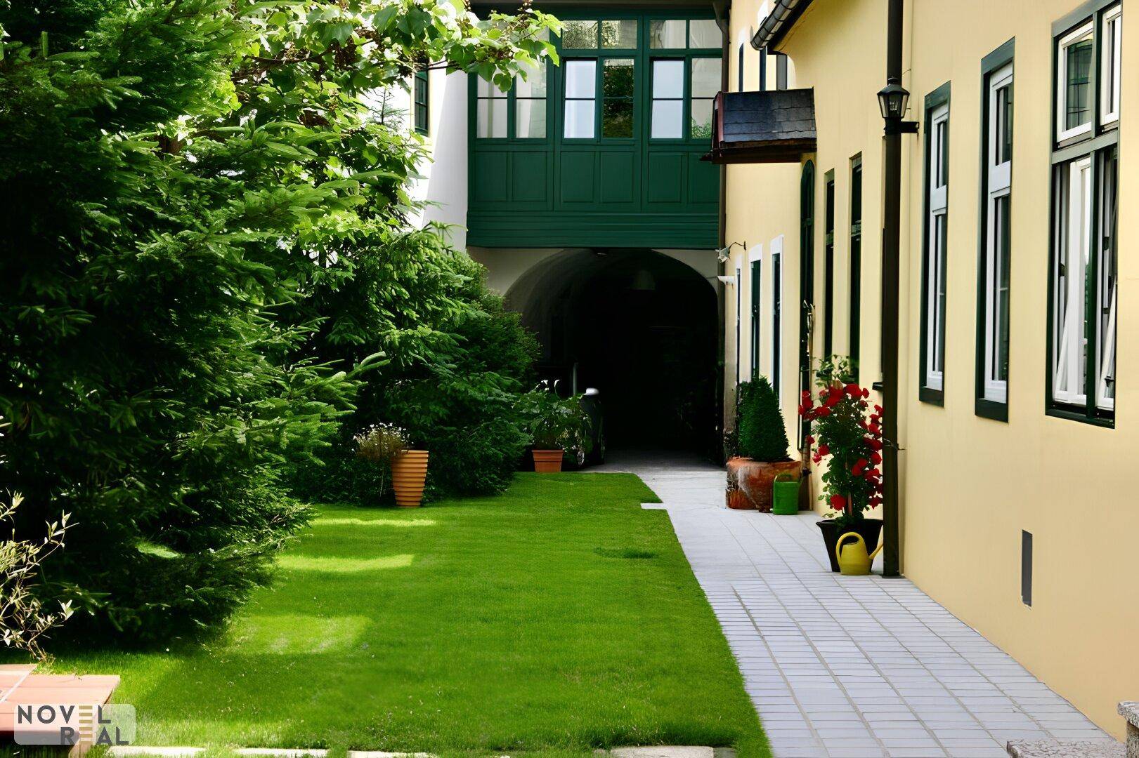 Gepflegter Gartenbereich mit Rasenfläche und einem Weg, der zu einem überdachten Durchgang führt.