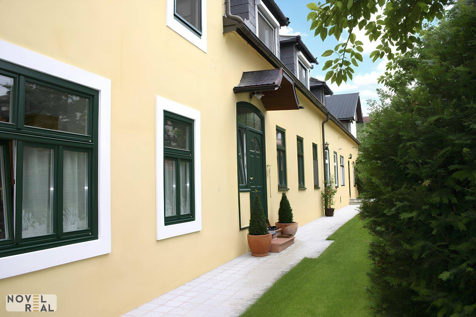 Historische Fassade eines Gebäudes mit gelbem Putz und grünen Fensterrahmen.