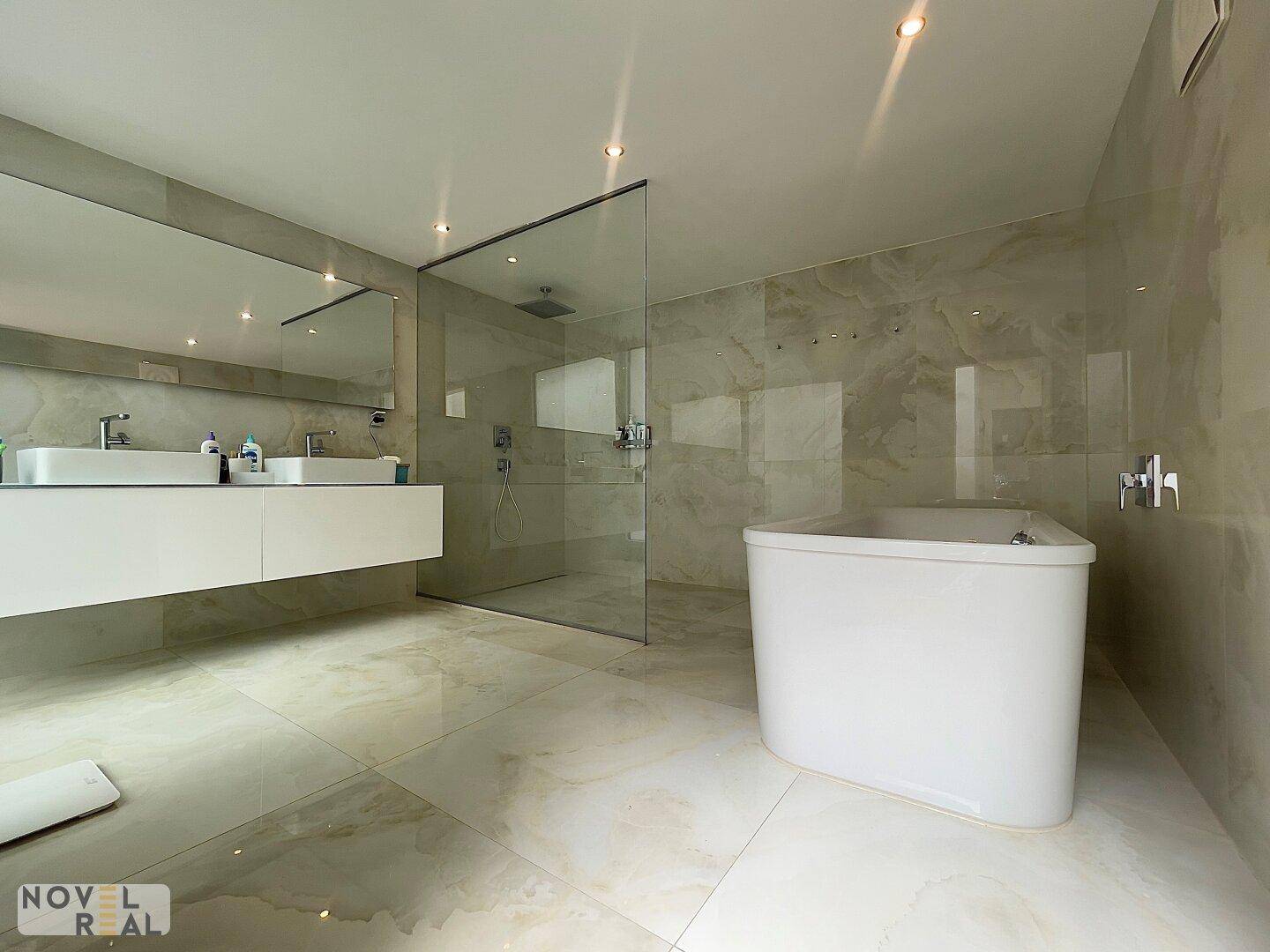 Luxuriöses Badezimmer mit Doppelwaschbecken, großer begehbarer Dusche und freistehender Badewanne.
