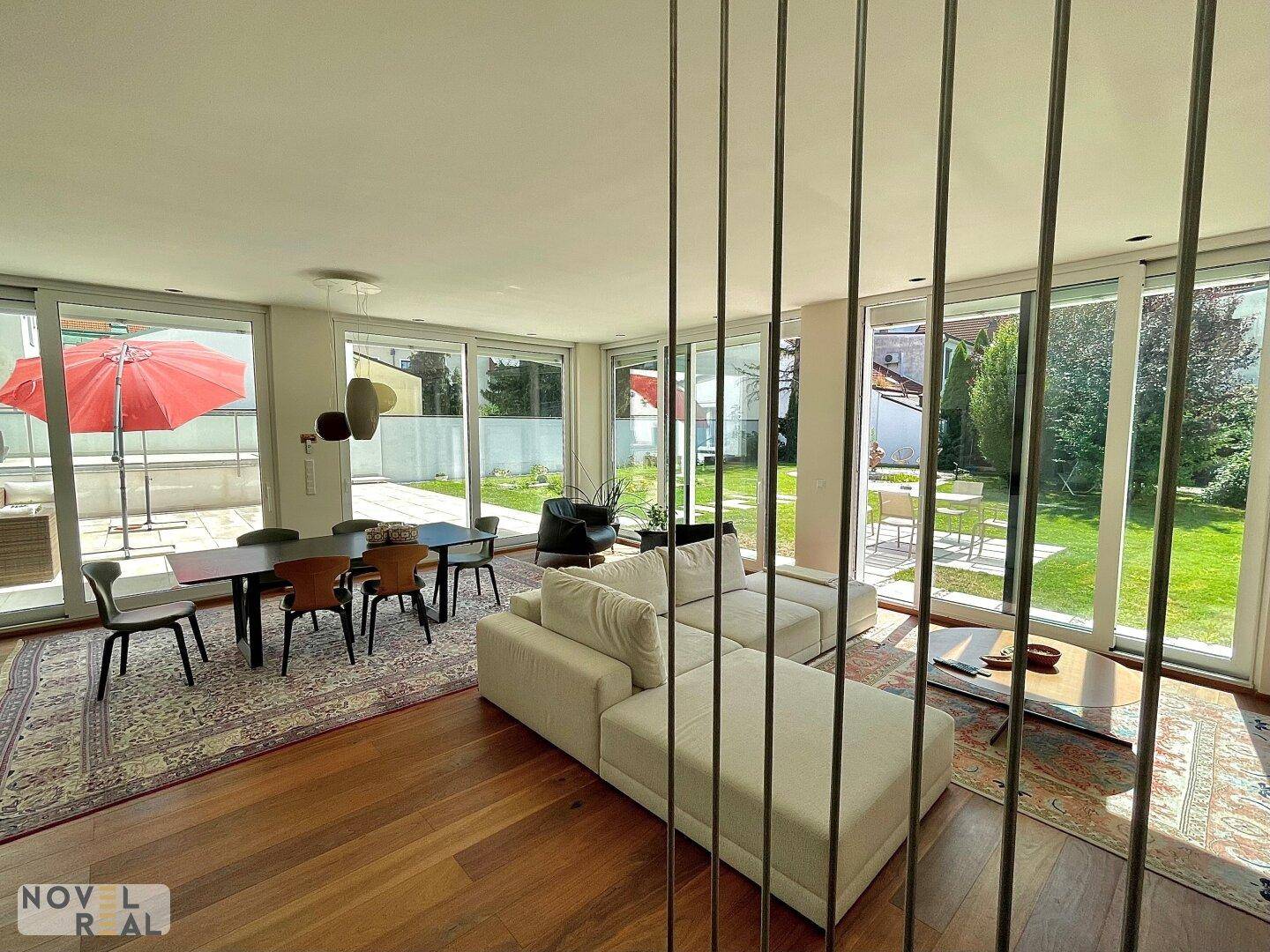 Geräumiger Wohn-Essbereich mit bequemer Couch, Esstisch und weitem Blick in den grünen Garten.
