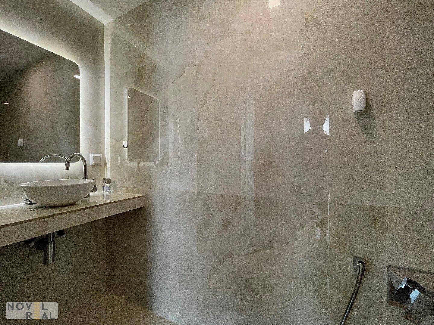 Modernes Badezimmer mit elegantem Waschbecken und großformatigen Fliesen in Marmoroptik.