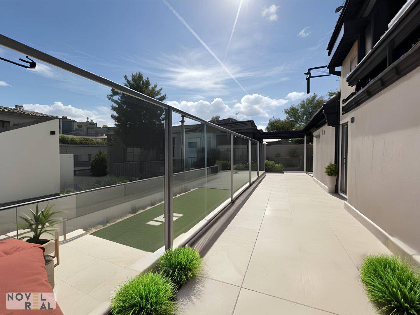 Weitläufige Dachterrasse mit Glasgeländer, Kunstrasen und sonnigem Ausblick über die Umgebung.