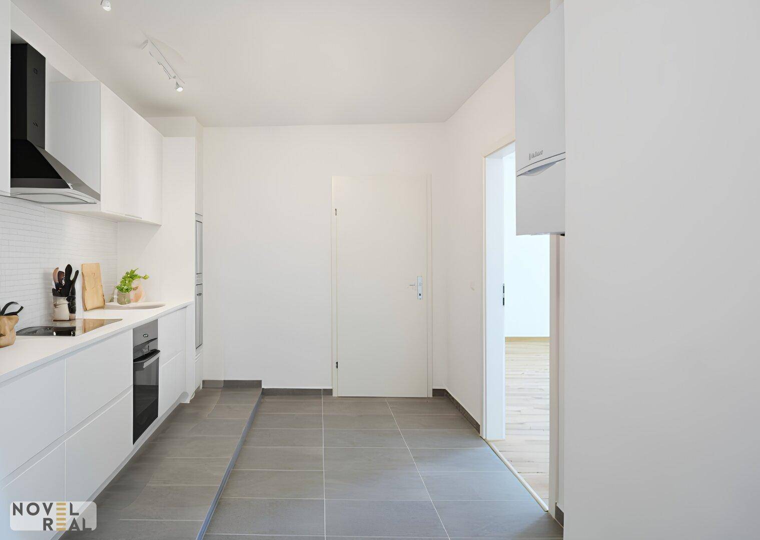 Moderne, helle Küche mit weißen Schränken, integrierten Geräten und Fliesenboden.