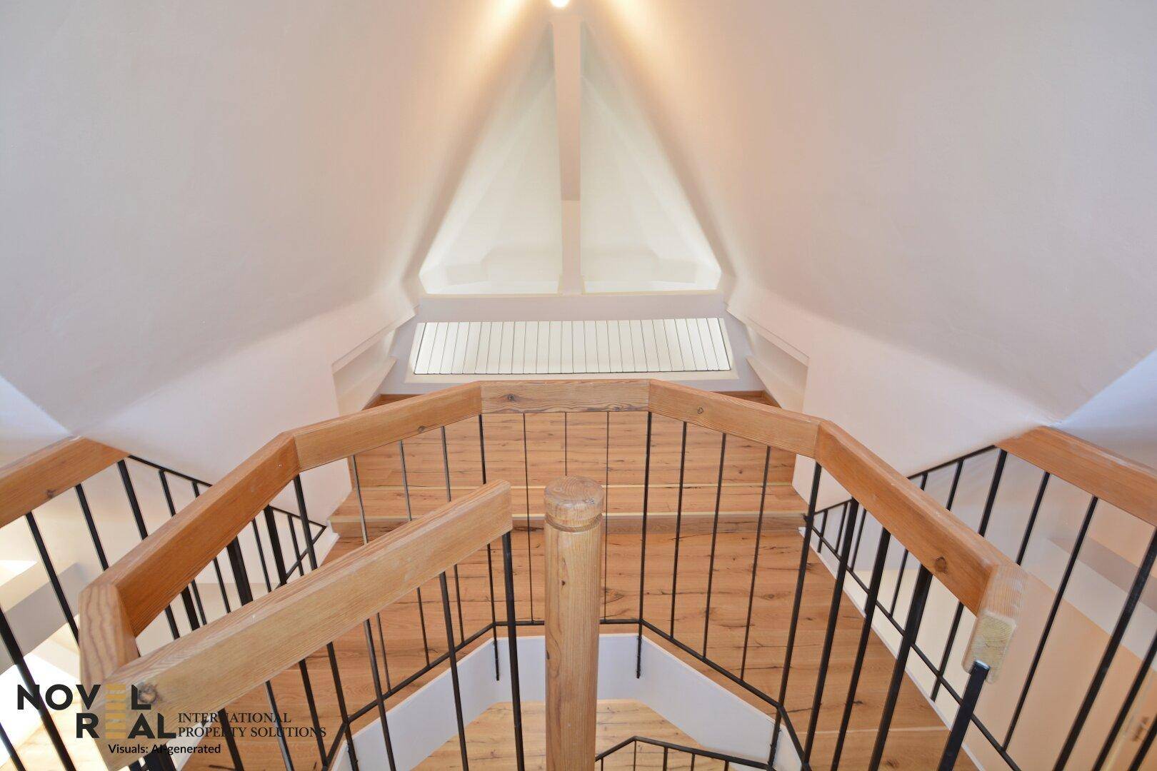 Draufsicht auf eine mehrstöckige Holztreppe mit schwarzem Geländer und hellem Holzfußboden.