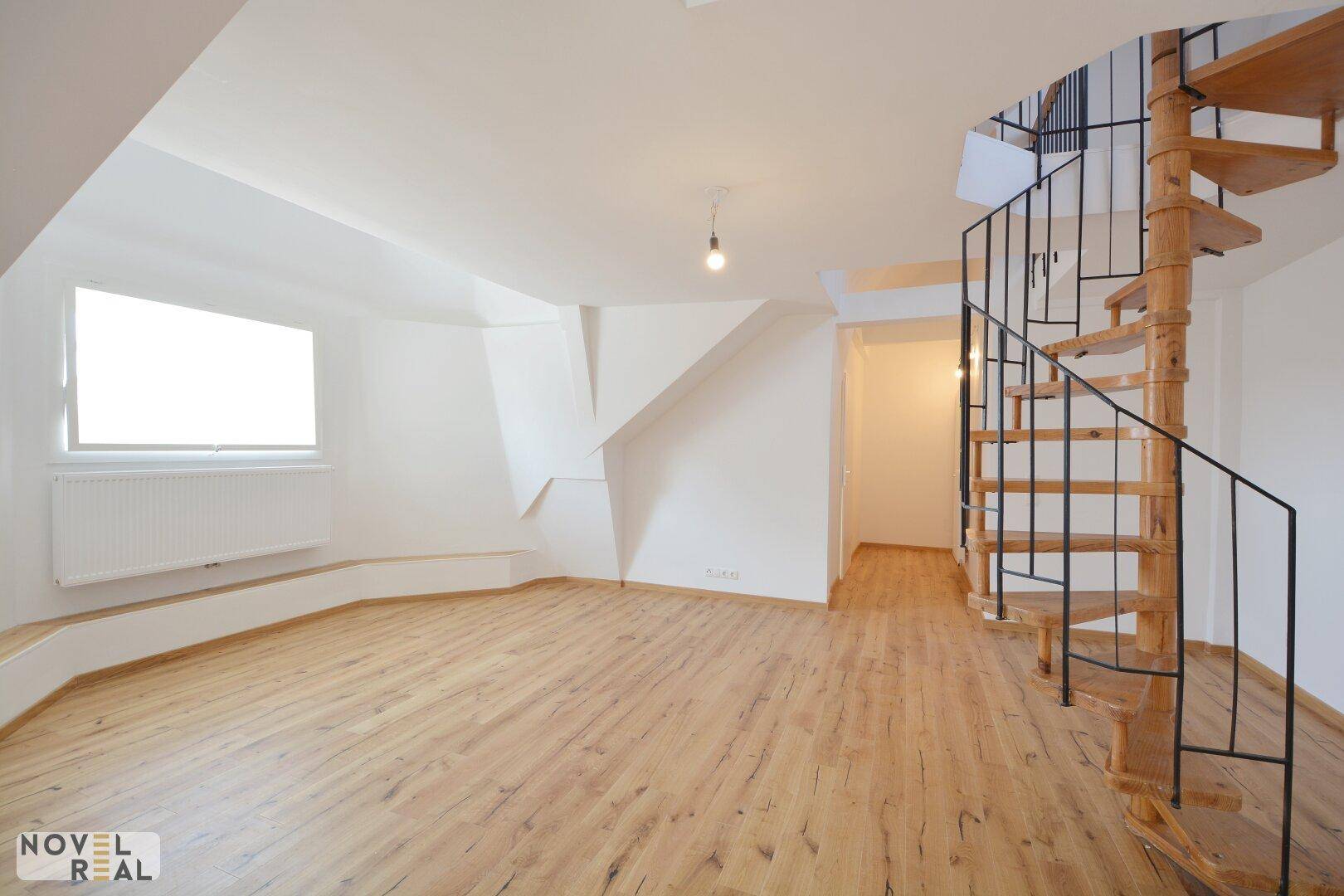 Heller, leerer Raum mit Laminatboden, Fenster und einer eleganten Holz-Wendeltreppe.
