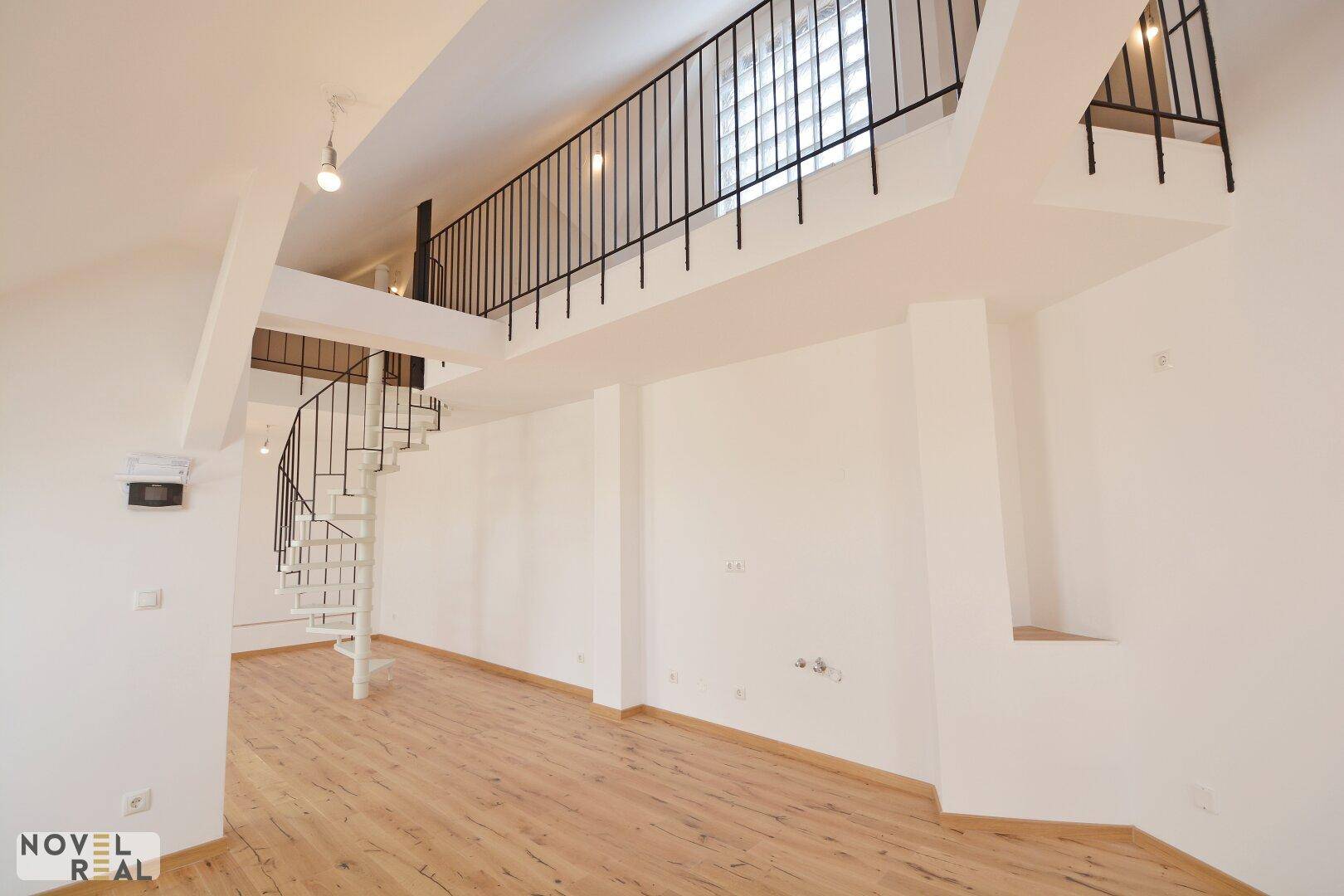 Geräumige, unmöblierte Wohnfläche mit hoher Decke und eleganter Wendeltreppe zur Galerieebene.