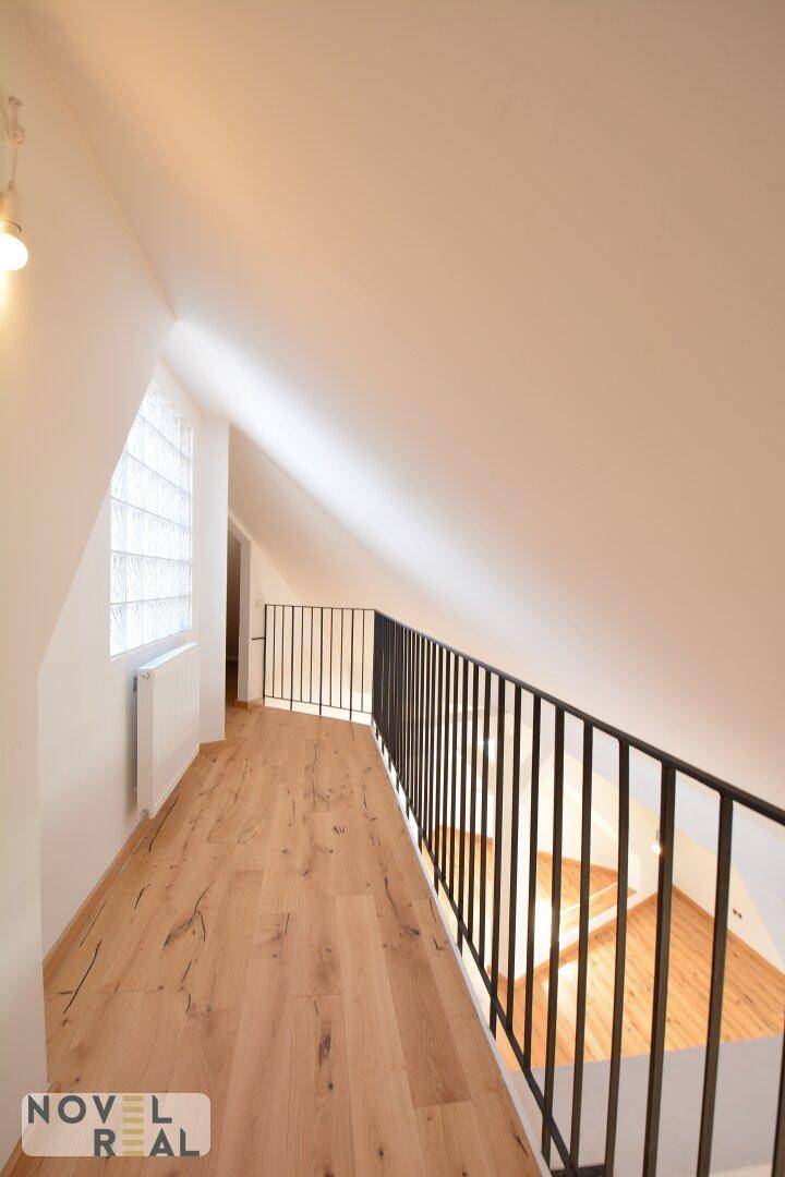 Galeriebereich mit Geländer, Holzfußboden und Glasbausteinfenster, das für zusätzliches Licht sorgt.