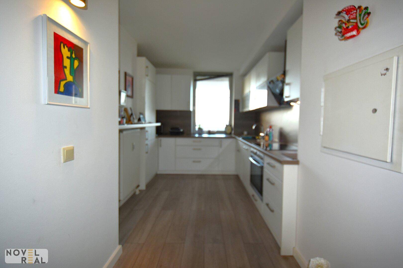 Funktionale Küche mit weißen Schränken, modernen Geräten und Fenster für Tageslicht.