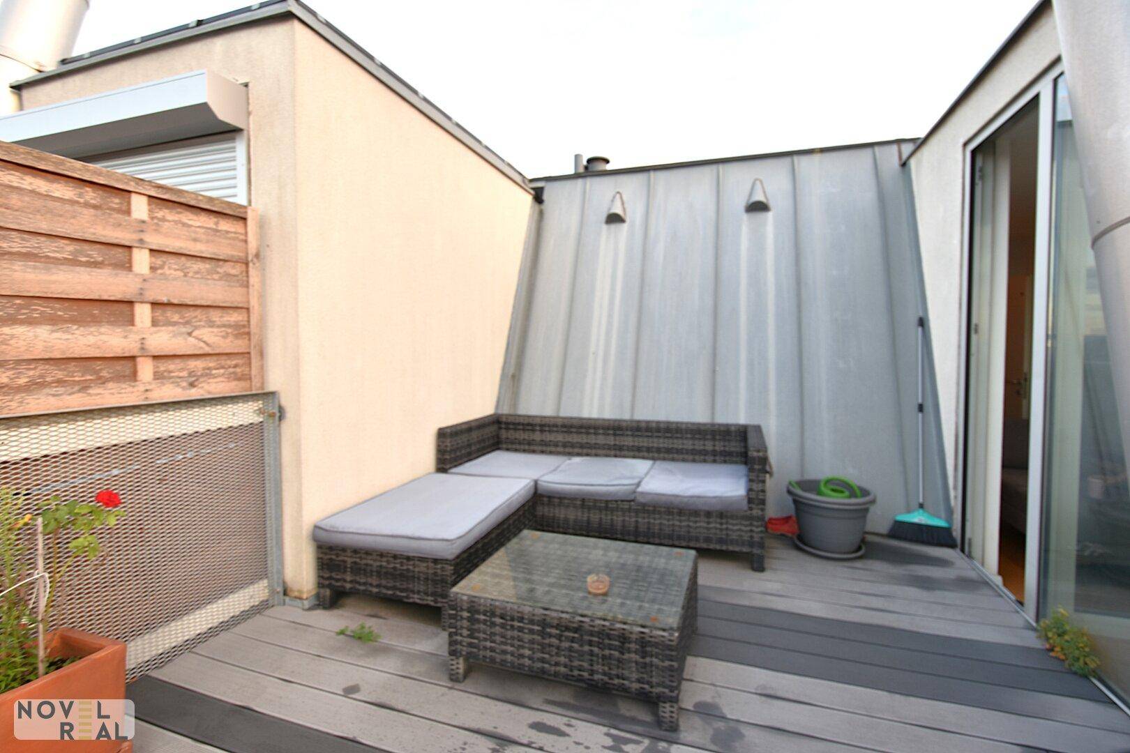 Gemütliche Dachterrasse mit Loungemöbeln und Holzboden, ideal zum Entspannen im Freien.