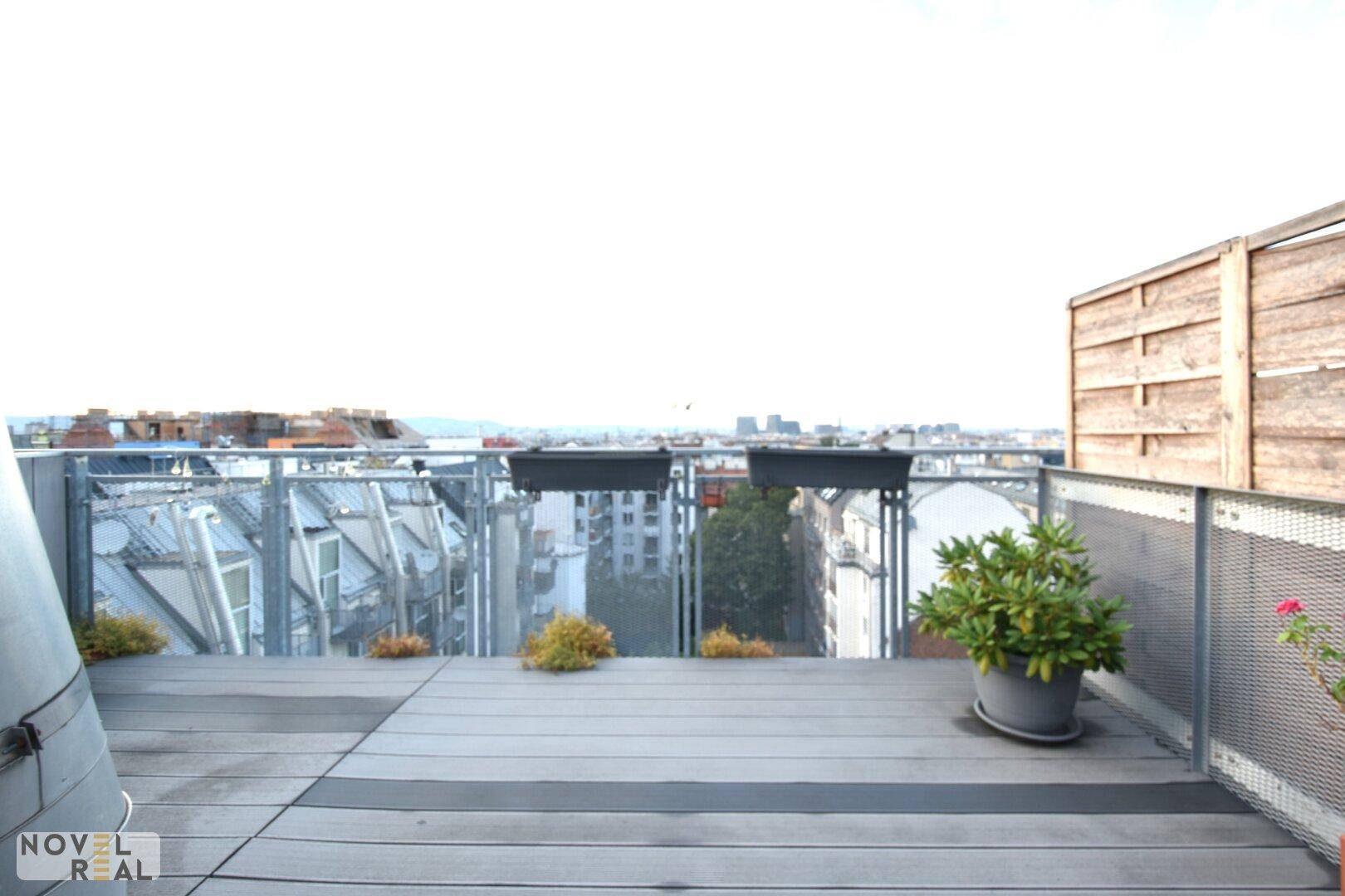 Geräumige Dachterrasse mit Holz-Kunststoff-Dielenboden, Pflanzen und weitem Stadtpanorama.