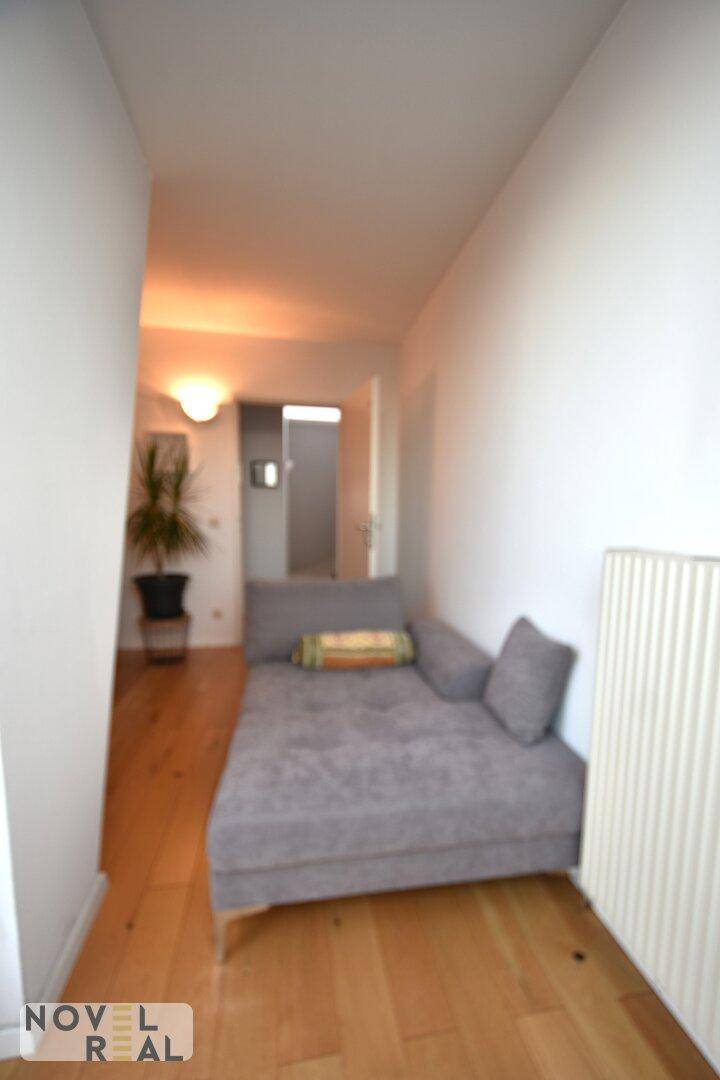 Schmaler Flur mit Holzboden und einer Liege, die zum Entspannen einlädt.