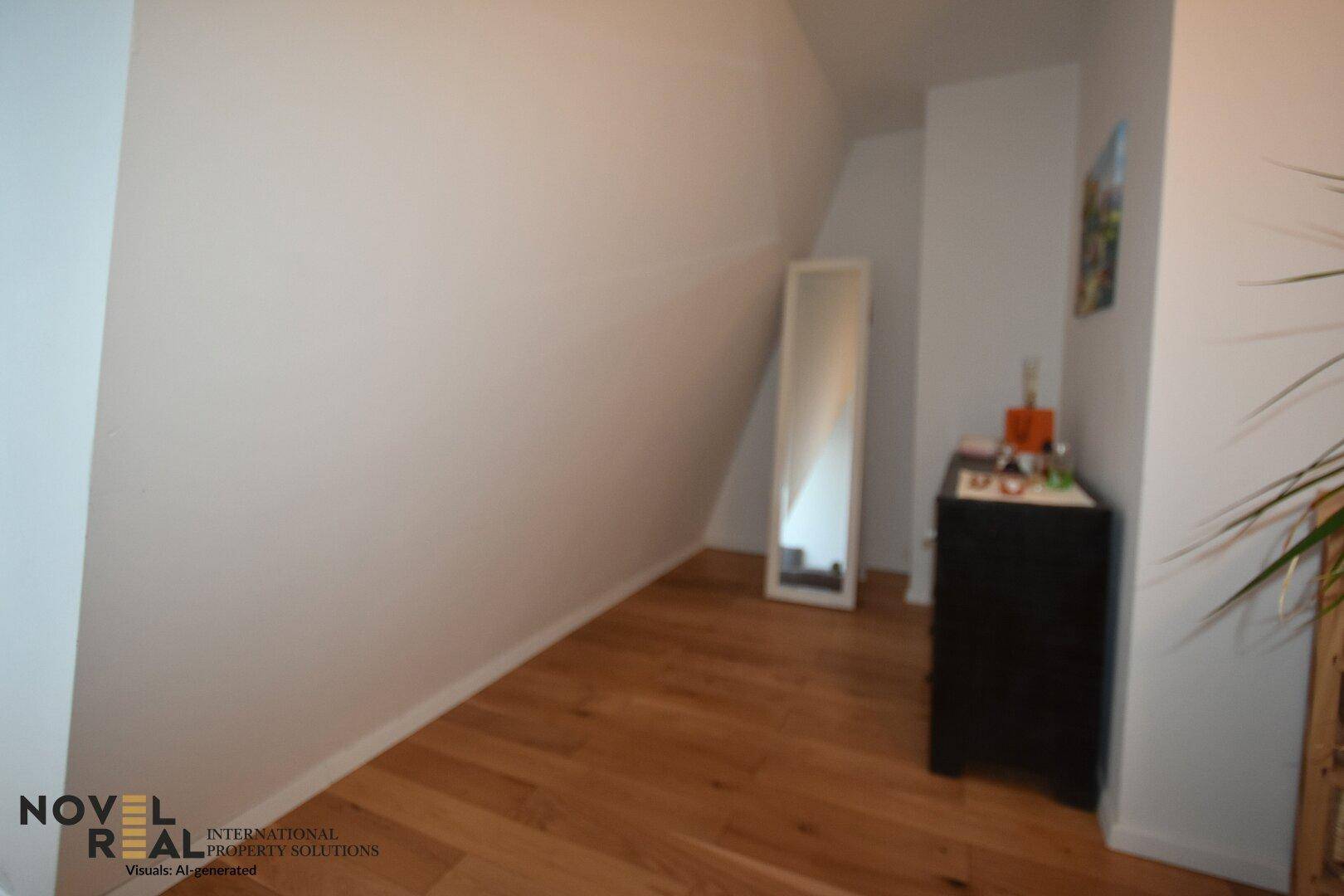 Schlafzimmer mit Dachschräge, Holzboden und einem schlichten Spiegel.