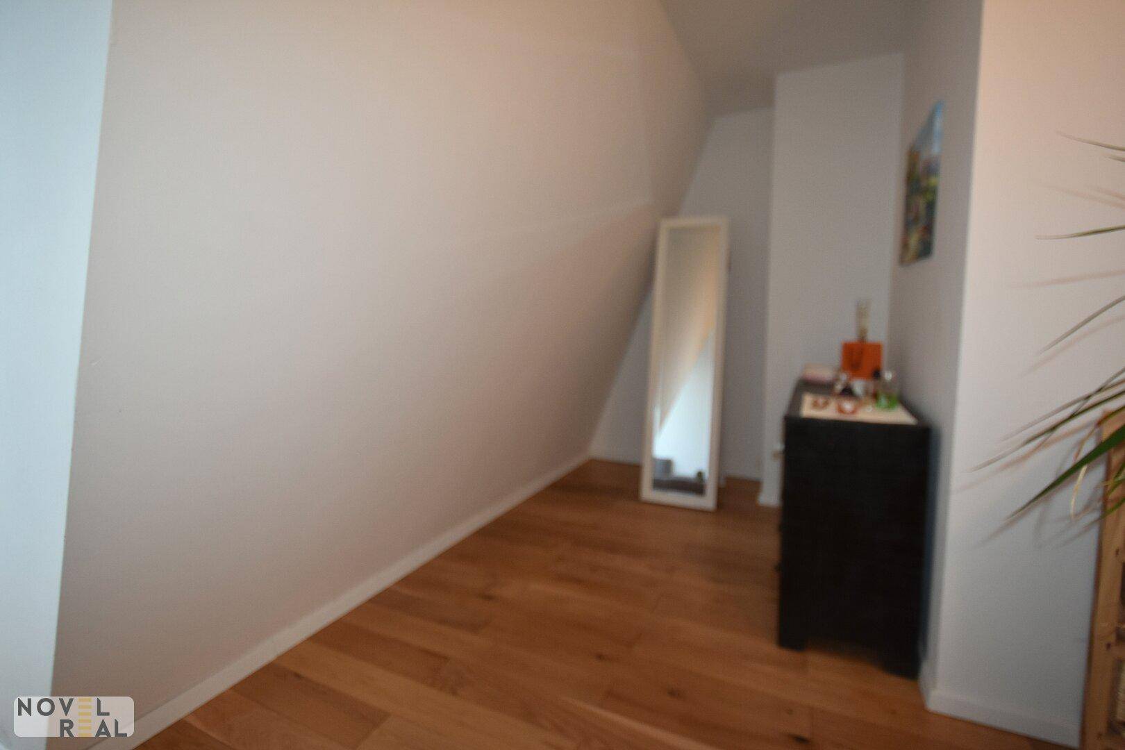 Raum mit Dachschräge, Holzboden und einem Spiegel, vielseitig nutzbar.