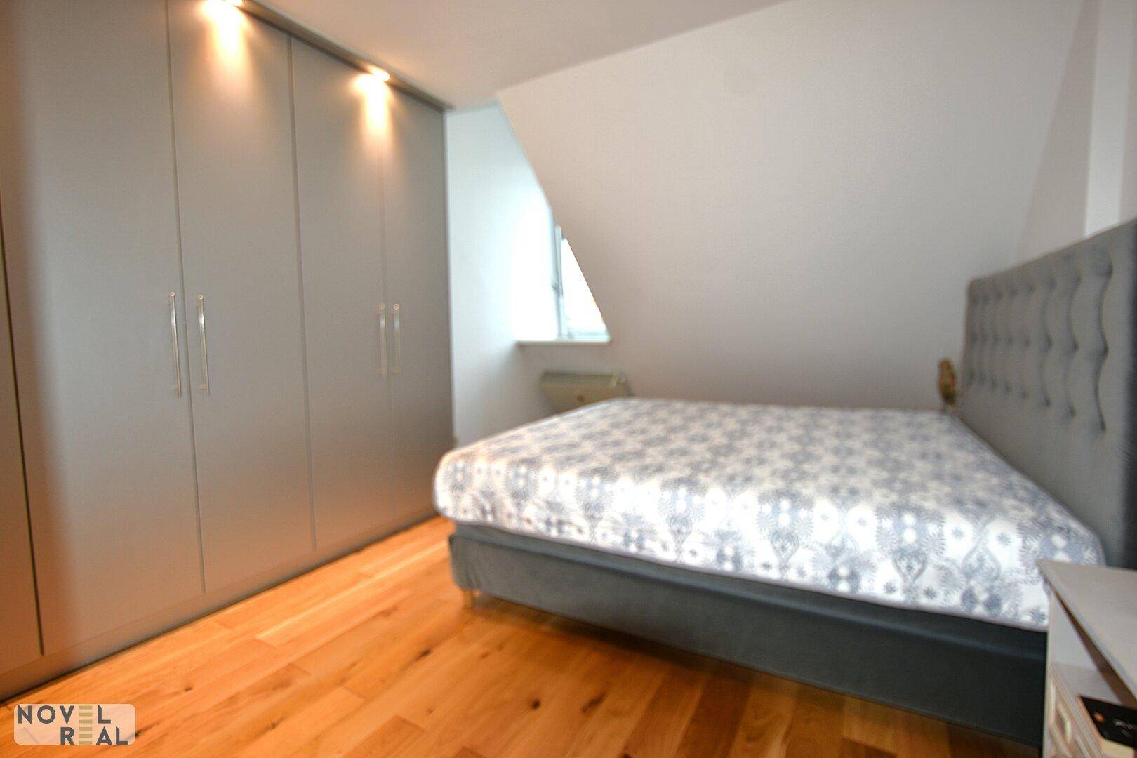Gemütliches Schlafzimmer mit Doppelbett, Einbauschränken und Dachschräge.