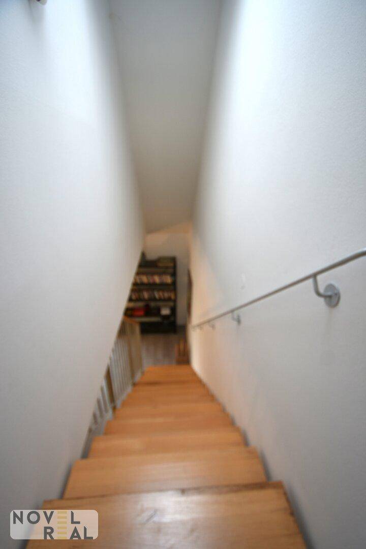 Helle Holztreppe mit Handlauf, die in den unteren Bereich des Hauses führt.