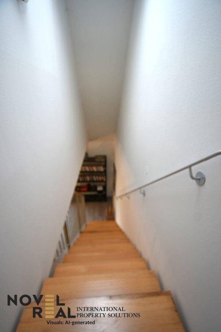 Holztreppe führt hinunter in einen hellen Flur mit schlichtem Geländer.