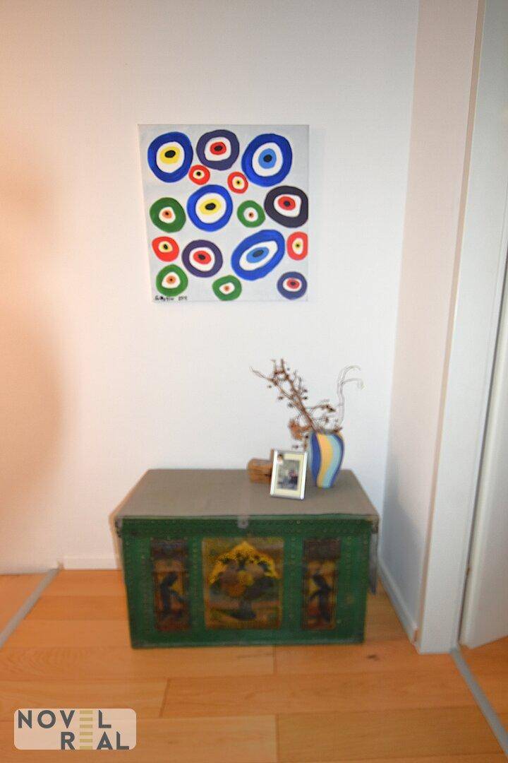 Dekorativer Flurbereich mit einer bunten Truhe und modernem Kunstwerk an der Wand.