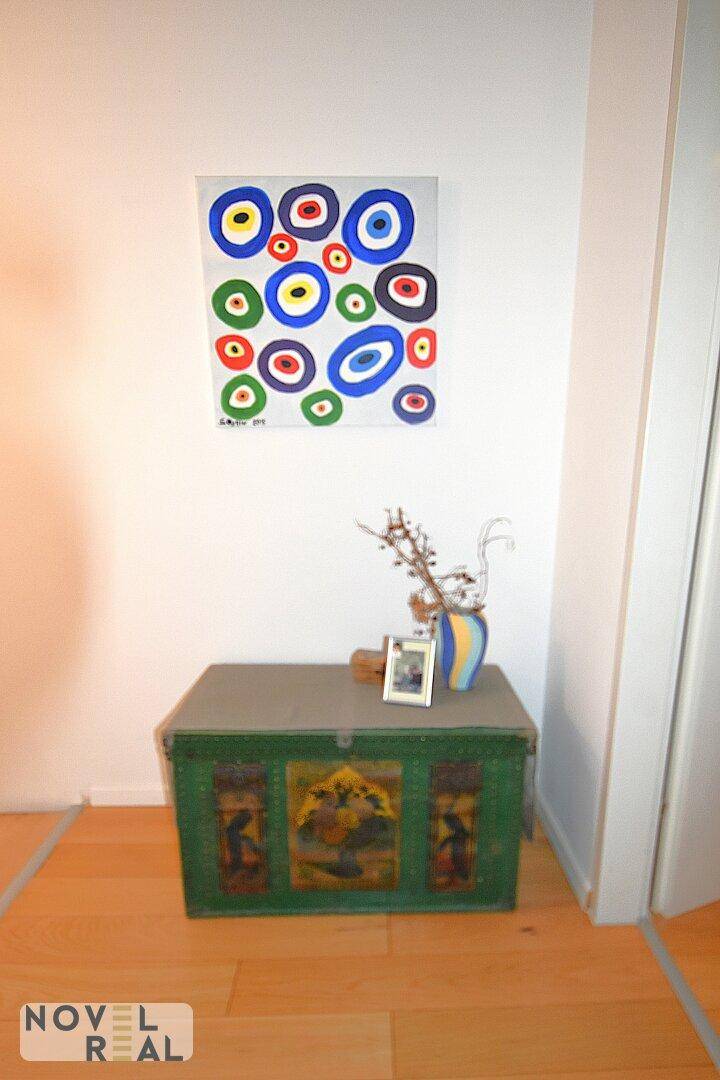 Dekorativer Flurbereich mit einer bunten Truhe und modernem Kunstwerk an der Wand.