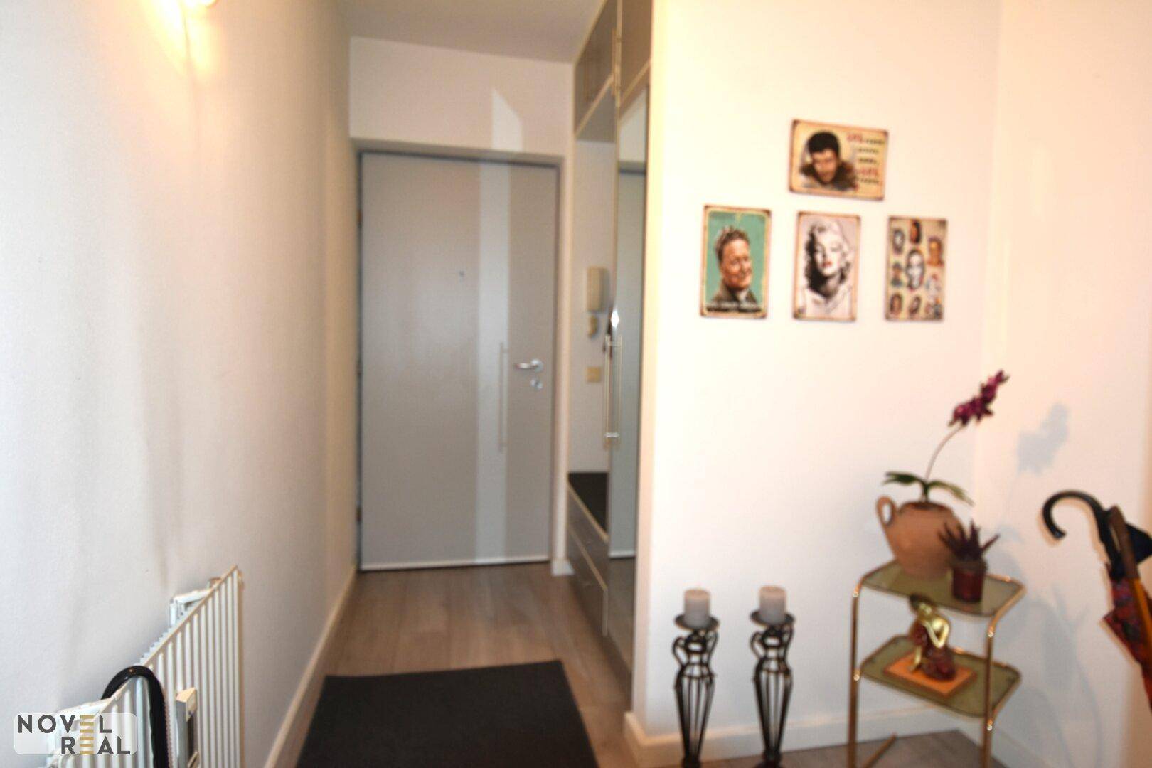 Eingangsbereich mit heller Tür, Garderobe und dekorativen Bildern an der Wand.