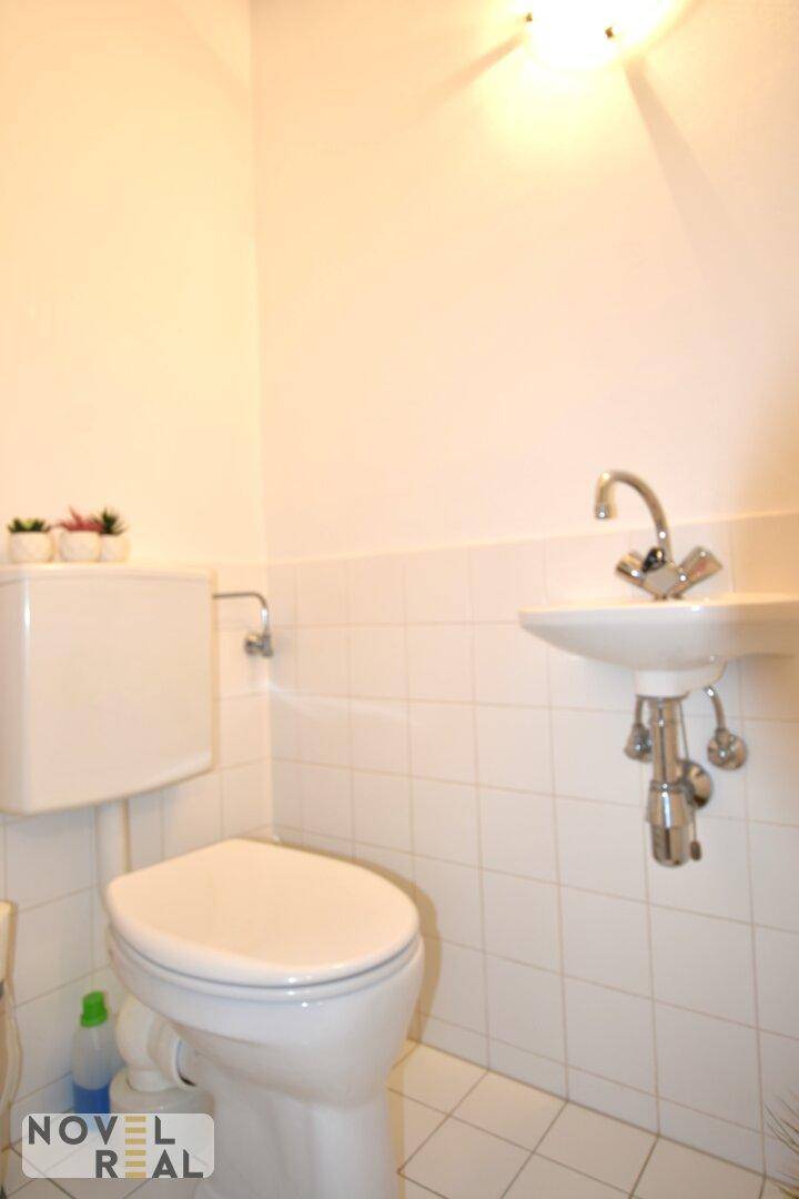 Kleines Gäste-WC mit Toilette, Waschbecken und weißen Fliesen.