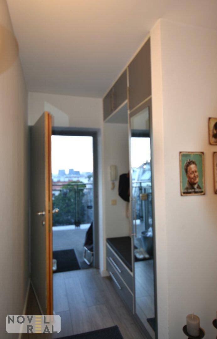 Heller Flur mit Einbauschränken, großem Spiegel und Zugang zu einem Balkon mit Stadtblick.