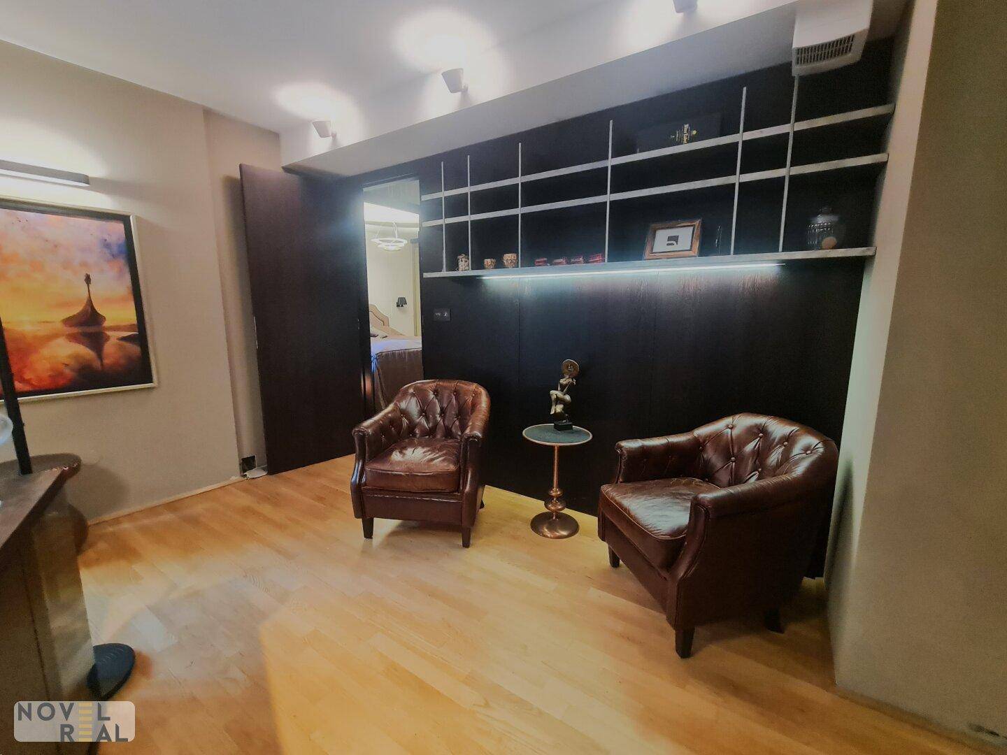 Gemütliche Sitzecke im Wohnzimmer mit Ledersesseln und einem eleganten Wandregal.
