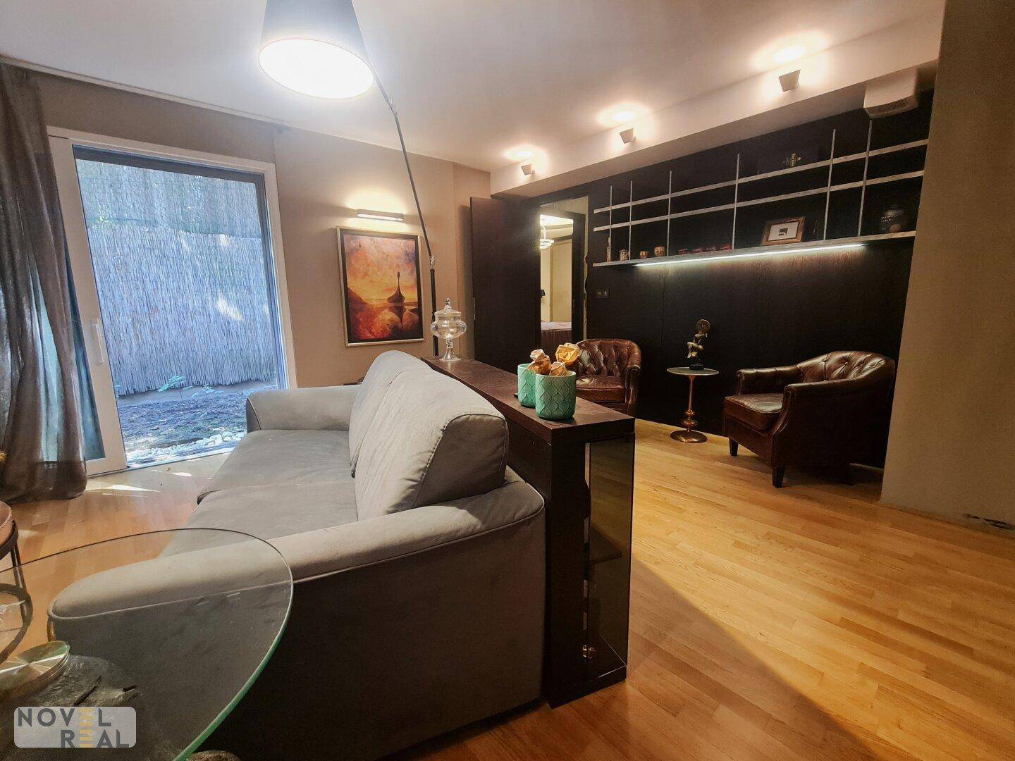 Blick vom Sofa auf die große Glastür, die zum Garten führt und viel Tageslicht hereinlässt.