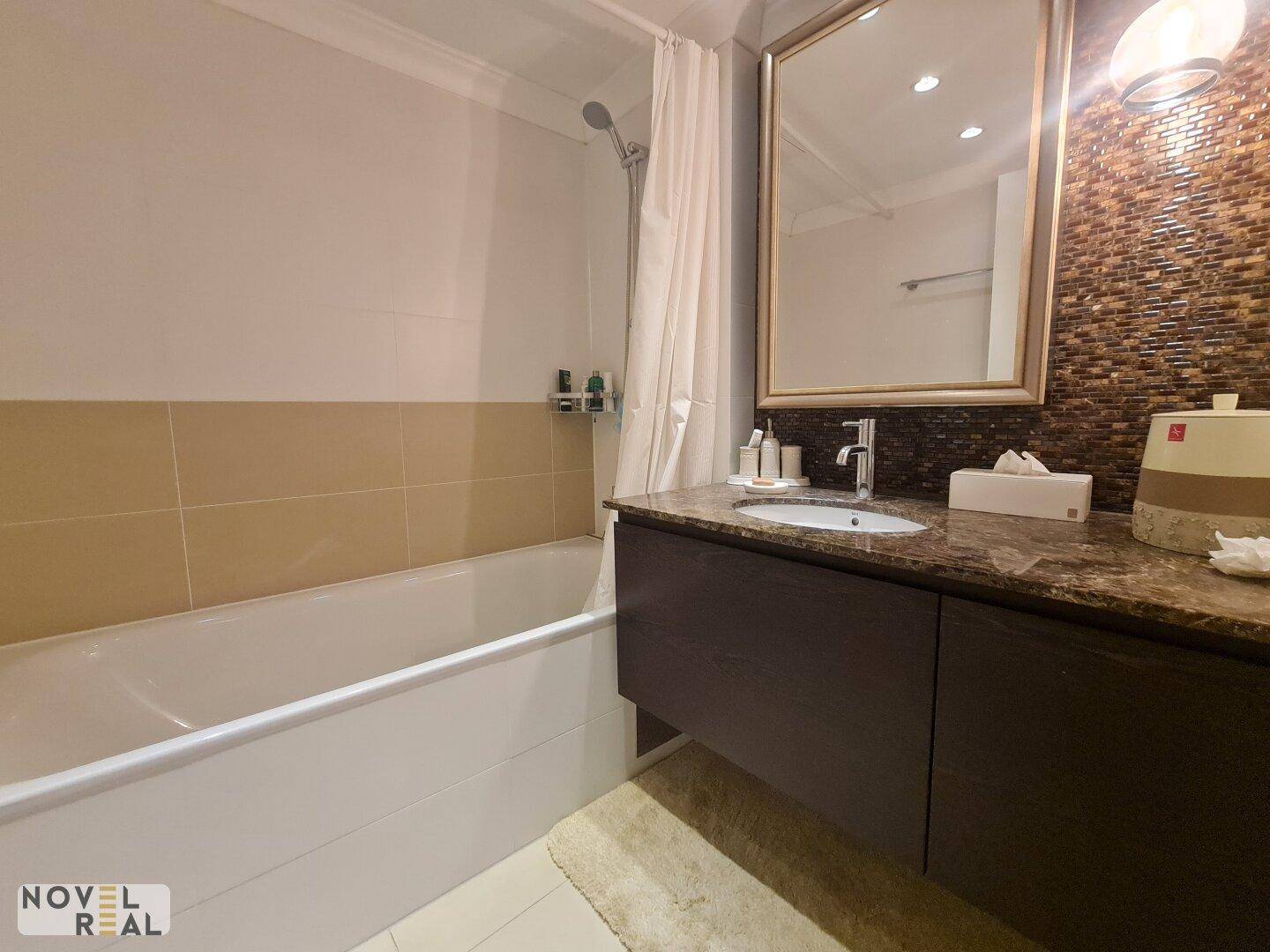 Badezimmer mit Badewanne, modernem Waschtisch und einem großen Spiegel.