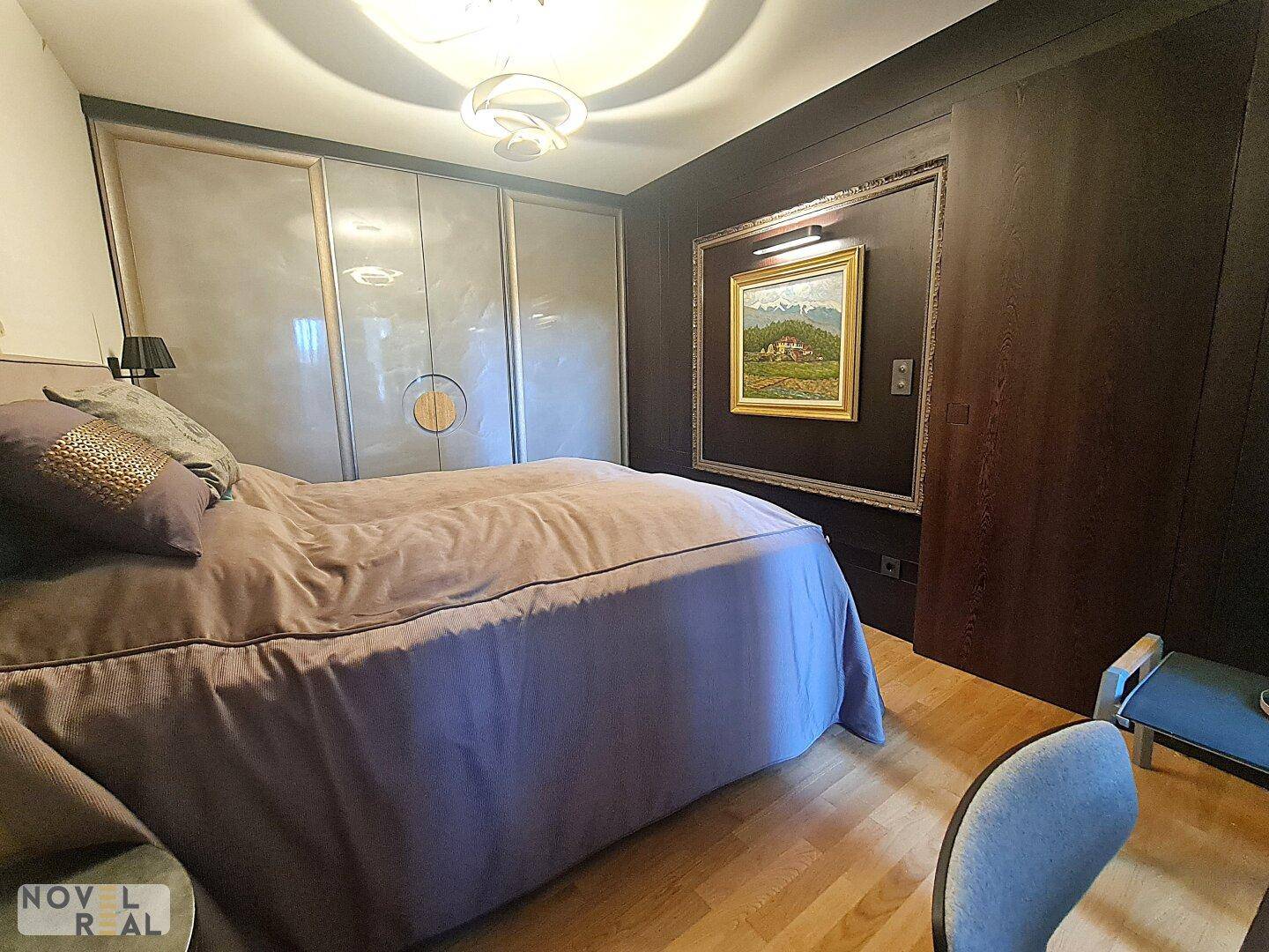 Schlafzimmer mit großem Bett, eleganten Einbauschränken und einem Kunstwerk an der Wand.