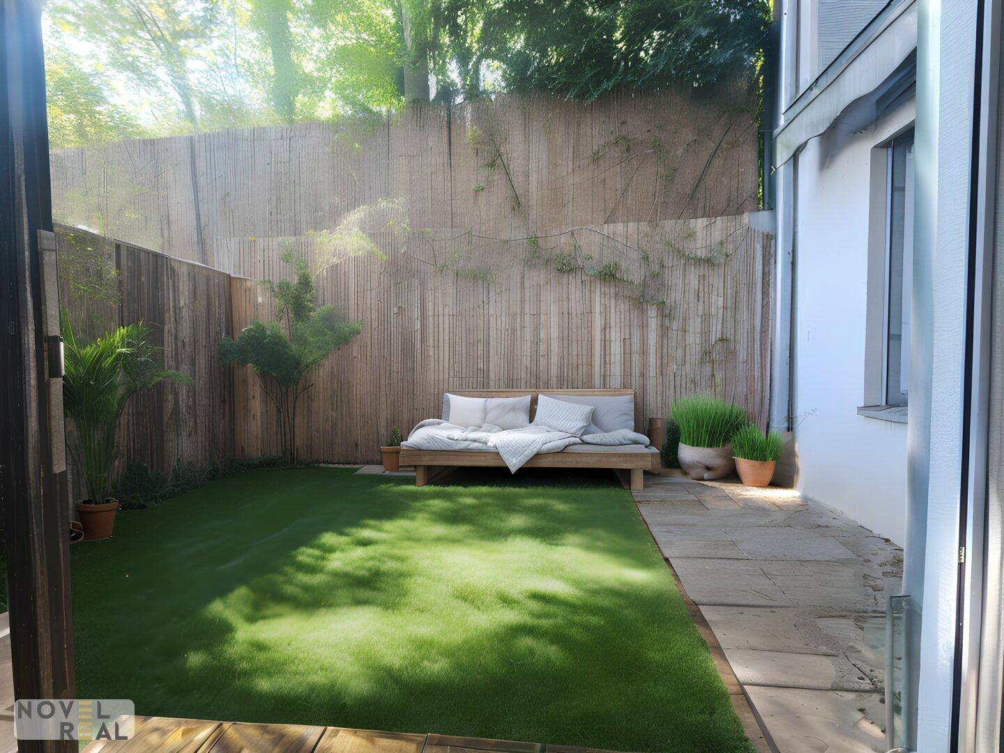 Kleiner, gepflegter Garten mit Kunstrasen, einer Holzliege und Bambuszaun für Privatsphäre.