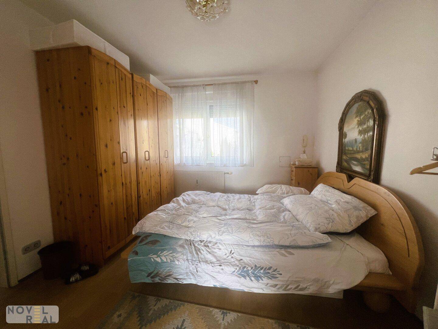 Geräumiges Schlafzimmer mit großem Holzkleiderschrank und Doppelbett, hell und freundlich.