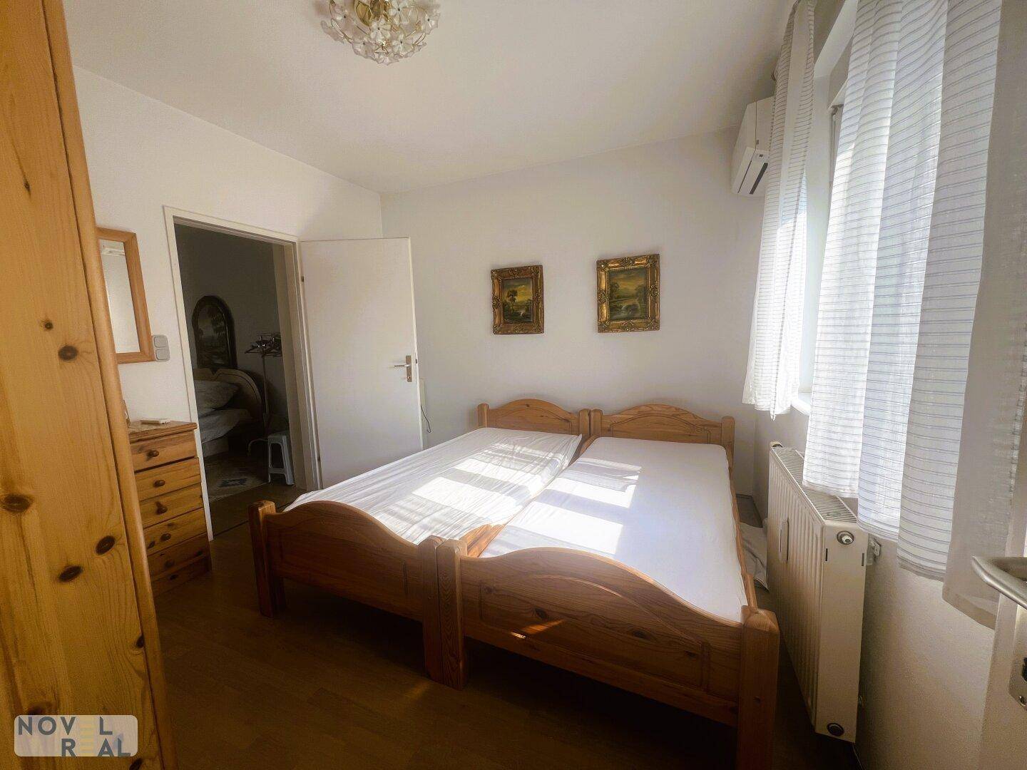 Gemütliches Schlafzimmer mit zwei Einzelbetten aus Holz, Parkettboden und Klimaanlage.